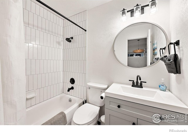bathroom featuring vanity, a textured wall, shower / bath combo, and toilet