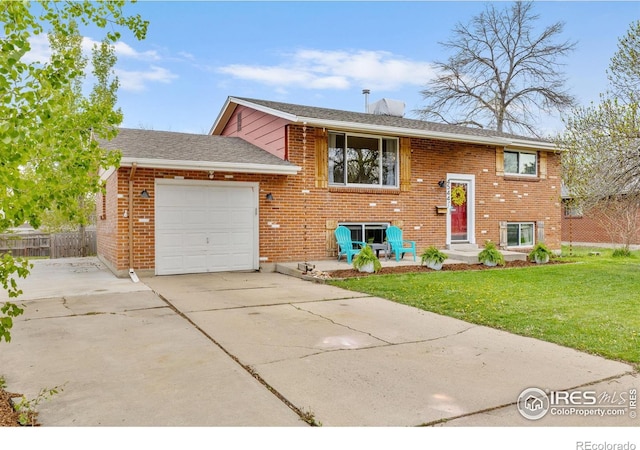 split foyer home with driveway, a garage, brick siding, fence, and a front lawn