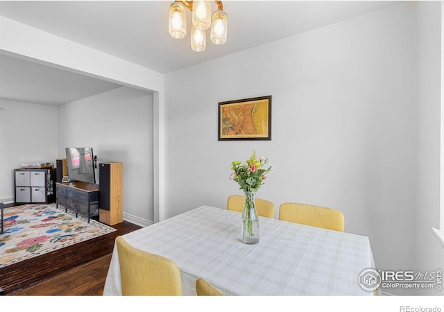 dining space with an inviting chandelier, baseboards, and dark wood-style floors