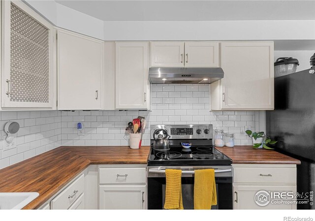 kitchen with stainless steel electric range, wood counters, freestanding refrigerator, white cabinetry, and under cabinet range hood