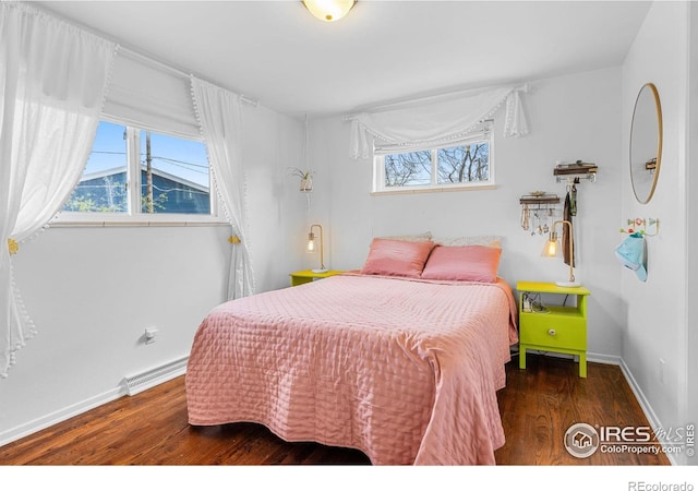 bedroom featuring baseboards, a baseboard heating unit, and wood finished floors