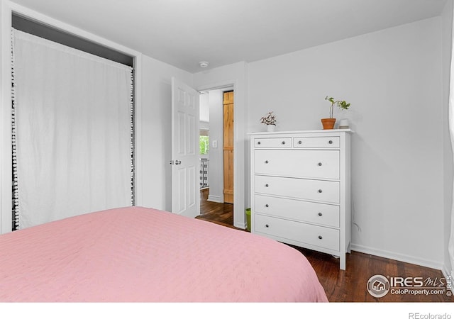 bedroom with dark wood-style flooring and baseboards