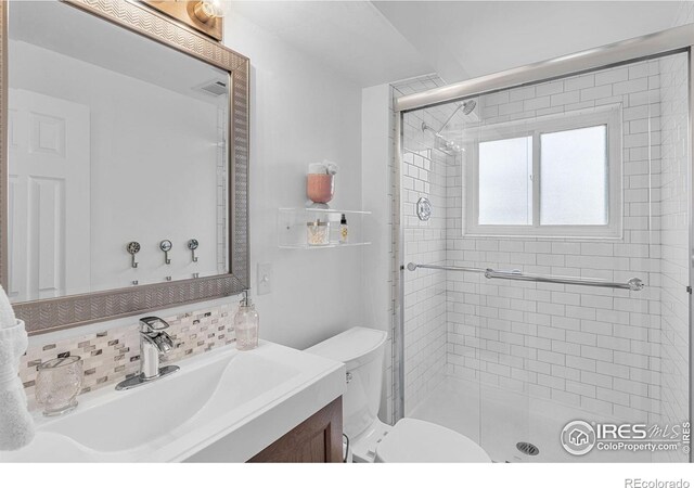 bathroom with vanity, tasteful backsplash, toilet, and a shower stall