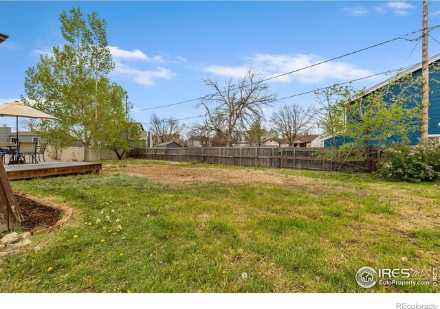 view of yard featuring a deck, a fenced backyard, and outdoor dining space