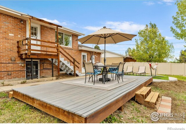 wooden deck with outdoor dining area, fence, and stairs