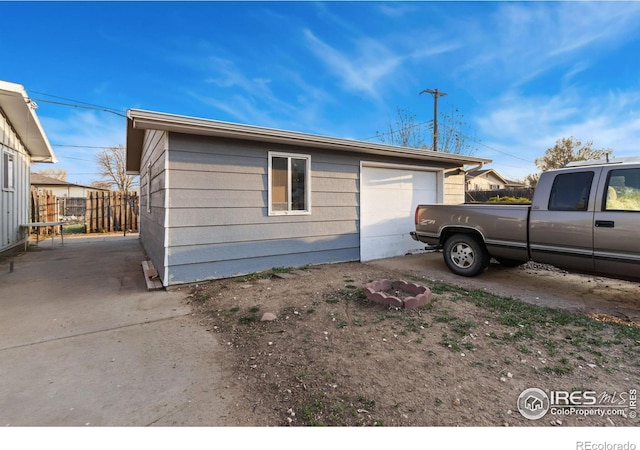 view of side of home featuring fence and a garage