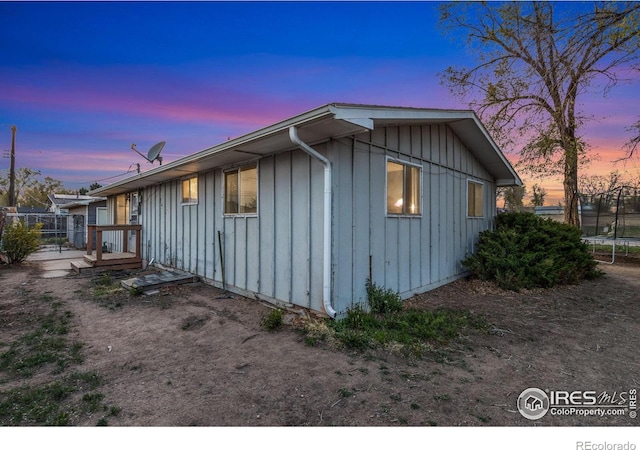property exterior at dusk featuring fence, a trampoline, and board and batten siding