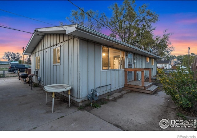 property exterior at dusk featuring board and batten siding and a patio