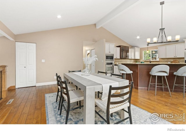 dining area with light wood-style floors, lofted ceiling with beams, baseboards, and visible vents
