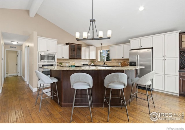 kitchen with visible vents, glass insert cabinets, a center island, tasteful backsplash, and stainless steel appliances