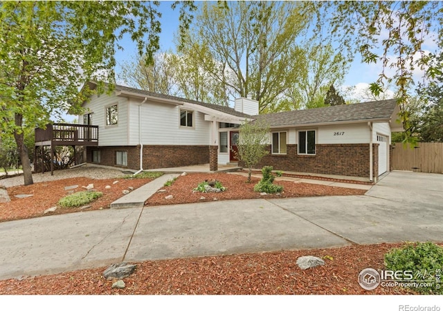2617 Treemont Dr, Fort Collins, CO 80524 - split level home featuring brick siding, an attached garage, a chimney, and a wooden deck