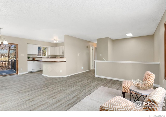 713 Boltz Dr, Fort Collins, CO 80525 - living room with baseboards, light wood finished floors, a textured ceiling, and a chandelier