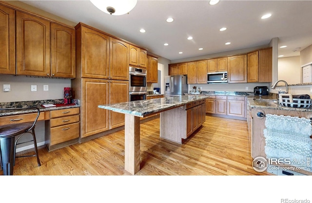 1442 Mallard Dr, Johnstown, CO 80534 - kitchen featuring appliances with stainless steel finishes, a sink, dark stone counters, a breakfast bar, and light wood-style floors