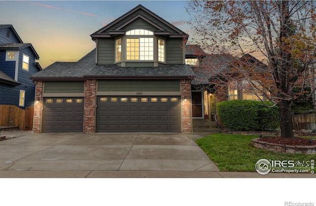 1442 Mallard Dr, Johnstown, CO 80534 - view of front of house with brick siding, concrete driveway, fence, and a shingled roof