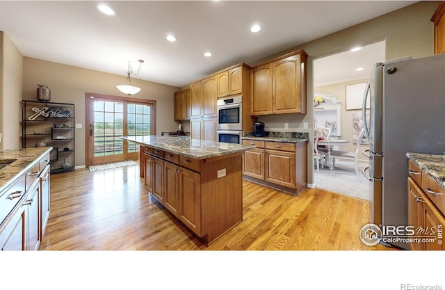1442 Mallard Dr, Johnstown, CO 80534 - kitchen with appliances with stainless steel finishes, a center island, light wood finished floors, recessed lighting, and light stone counters