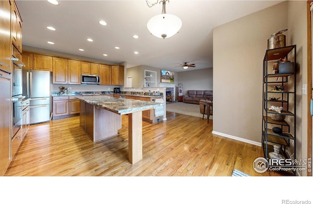 1442 Mallard Dr, Johnstown, CO 80534 - kitchen featuring appliances with stainless steel finishes, a center island, recessed lighting, light wood-style flooring, and a fireplace