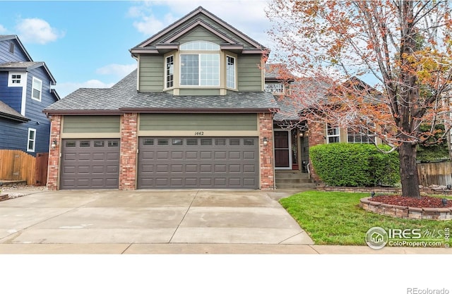 1442 Mallard Dr, Johnstown, CO 80534 - view of front facade with brick siding, fence, concrete driveway, a garage, and a shingled roof