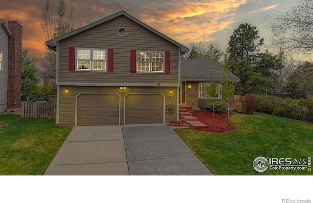 tri-level home with a yard, an attached garage, fence, and concrete driveway