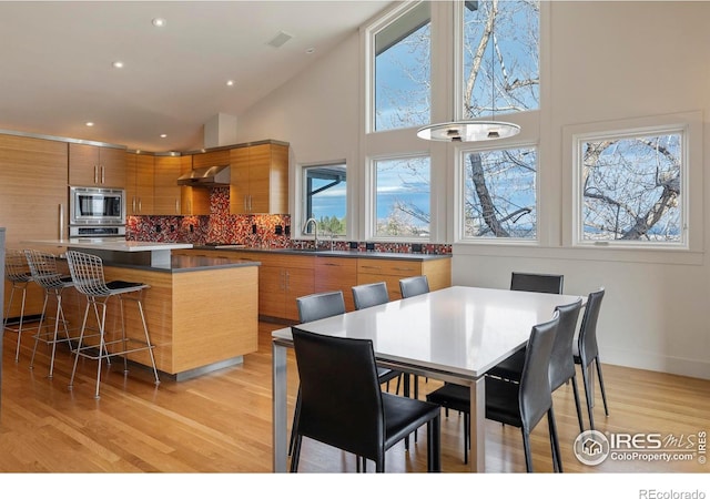 dining area featuring recessed lighting, baseboards, light wood-style flooring, and a towering ceiling