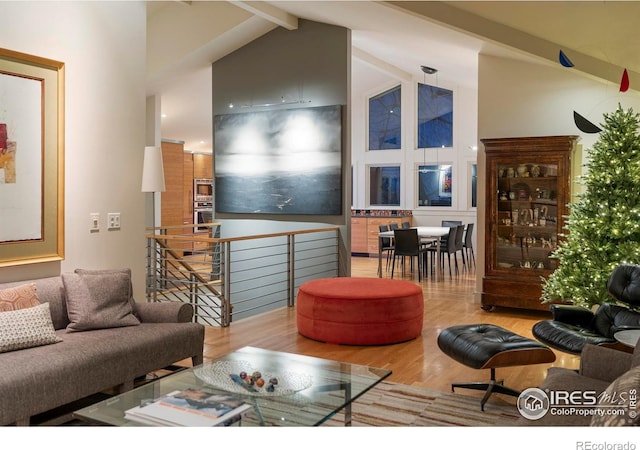 living area with high vaulted ceiling, beamed ceiling, and wood finished floors