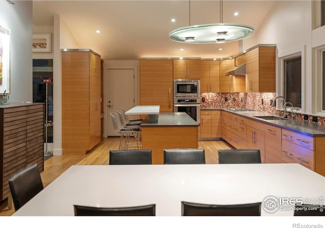 kitchen featuring ventilation hood, a center island, stainless steel appliances, tasteful backsplash, and modern cabinets