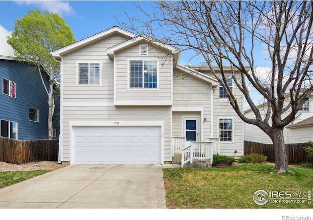 traditional-style house with an attached garage, fence, driveway, and a front yard