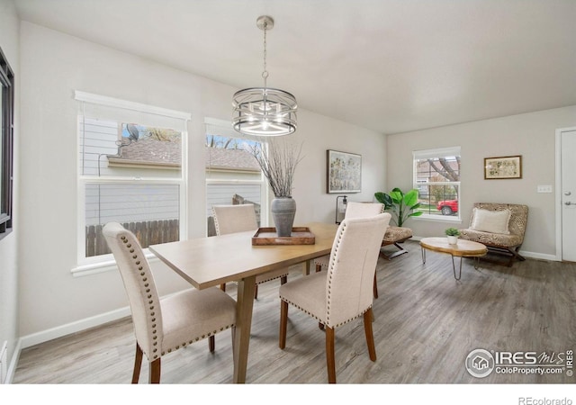 dining room with baseboards, light wood finished floors, and a notable chandelier