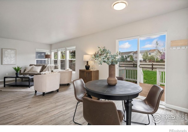 dining room with baseboards, light wood finished floors, and visible vents