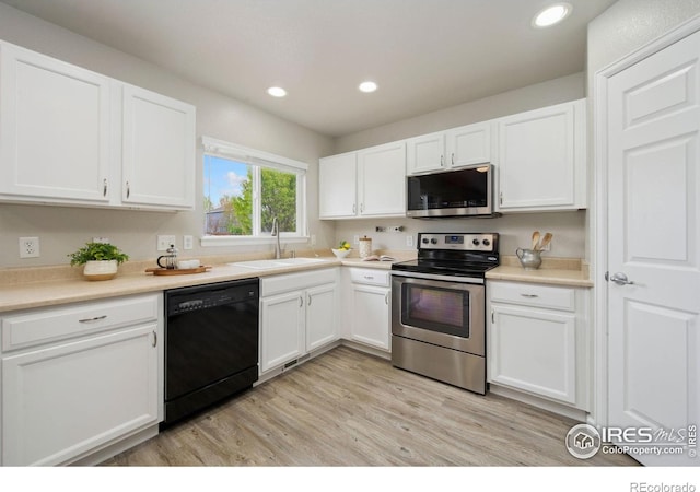 kitchen featuring light wood-style floors, a sink, appliances with stainless steel finishes, and white cabinets