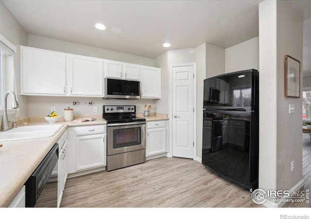 kitchen with a sink, light wood-style flooring, appliances with stainless steel finishes, and white cabinets