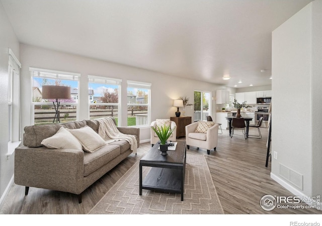 living area featuring recessed lighting, baseboards, visible vents, and light wood finished floors