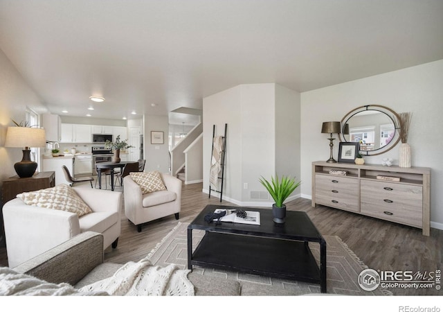 living area featuring recessed lighting, baseboards, stairs, and wood finished floors