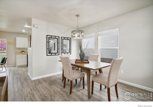 dining area featuring light wood-style floors, baseboards, and a chandelier