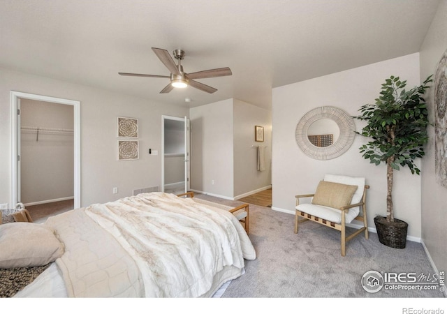bedroom with ceiling fan, baseboards, a closet, a spacious closet, and carpet