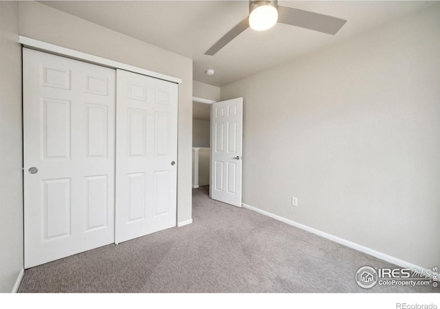 unfurnished bedroom with baseboards, carpet flooring, ceiling fan, and a closet