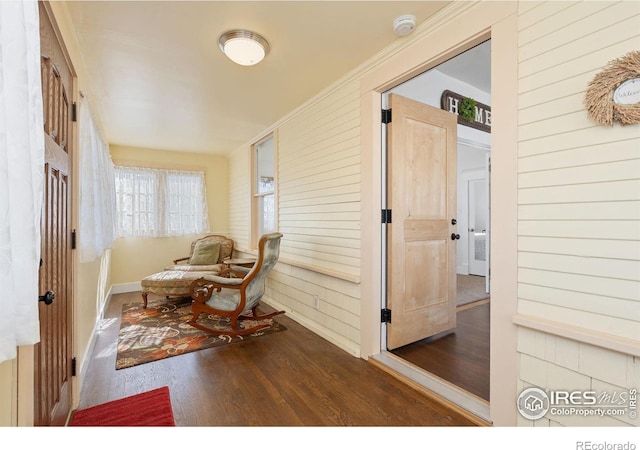 sitting room with baseboards, wood walls, and wood finished floors