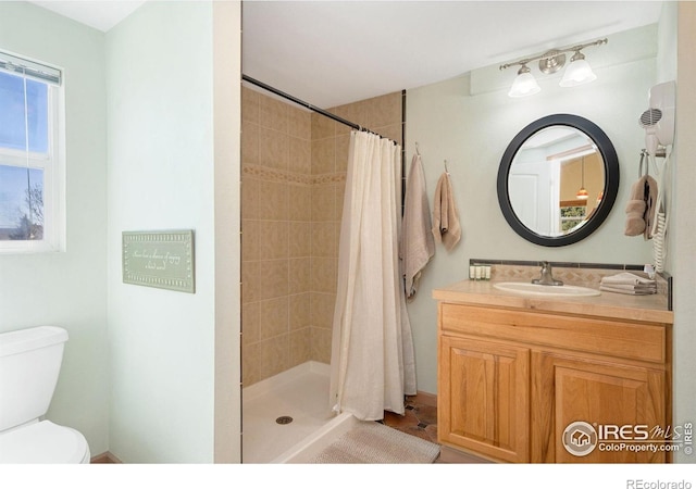 bathroom with toilet, a tile shower, and vanity