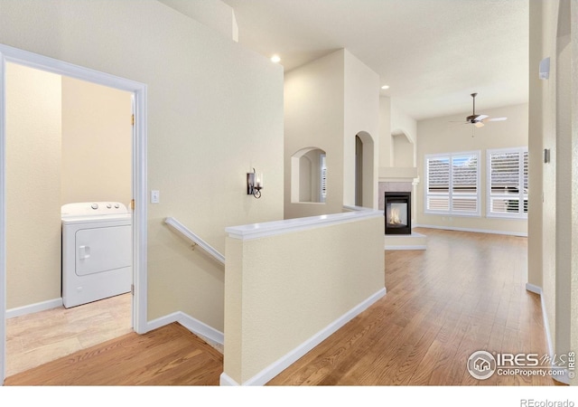 corridor with baseboards, light wood-style flooring, washer / dryer, and an upstairs landing