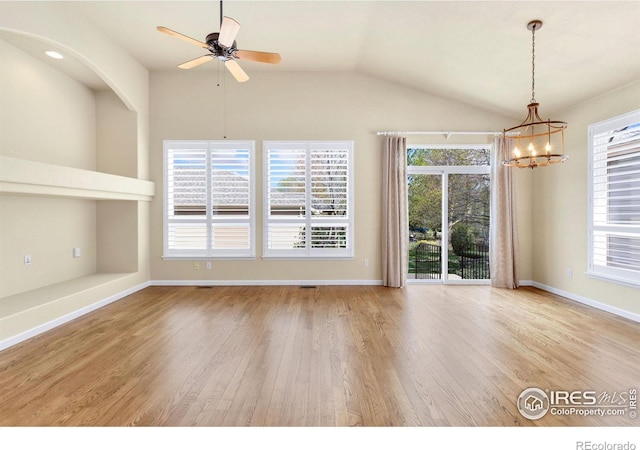 unfurnished room with baseboards, vaulted ceiling, wood finished floors, and ceiling fan with notable chandelier