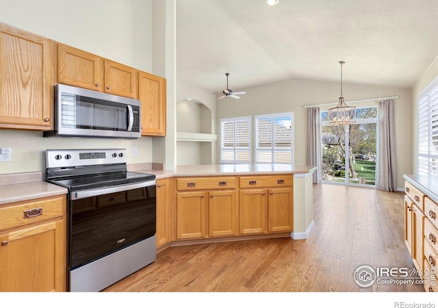 kitchen with a peninsula, lofted ceiling, light countertops, light wood-style flooring, and appliances with stainless steel finishes