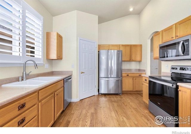 kitchen with light brown cabinetry, a sink, light countertops, light wood finished floors, and stainless steel appliances