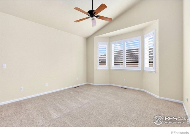 carpeted spare room featuring baseboards, ceiling fan, vaulted ceiling, and visible vents
