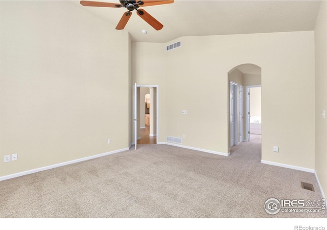 spare room featuring arched walkways, ceiling fan, light carpet, and visible vents