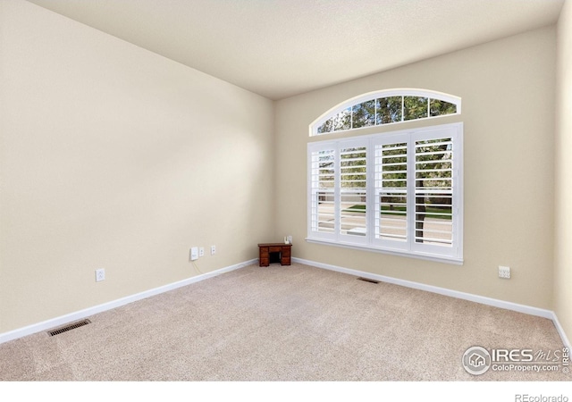 spare room featuring visible vents, carpet, and baseboards