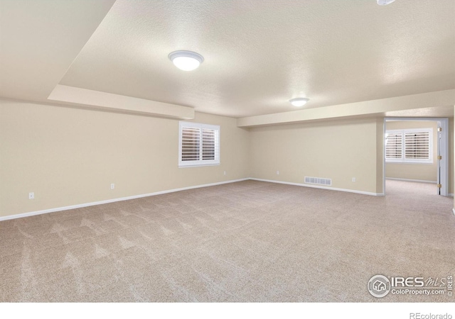 interior space with carpet flooring, a textured ceiling, baseboards, and visible vents