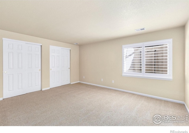unfurnished bedroom with carpet floors, baseboards, a textured ceiling, and visible vents