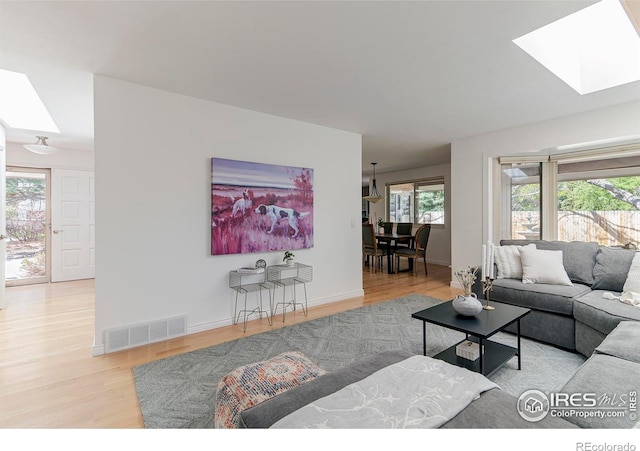 living area featuring a skylight, wood finished floors, and baseboards