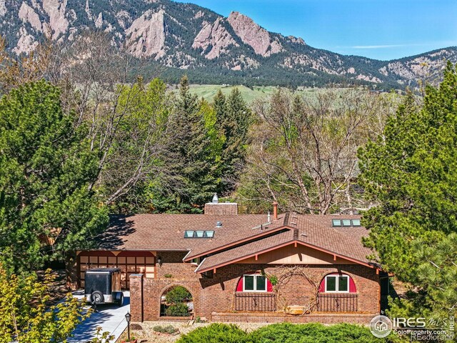view of front of property with brick siding, a mountain view, and a chimney