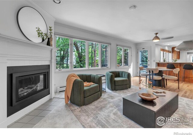 2672 Winding Trail Dr, Boulder, CO 80304 - tiled living area featuring a tiled fireplace, ceiling fan, crown molding, and baseboard heating