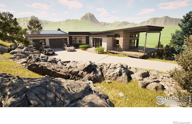 back of house featuring concrete driveway, a deck with mountain view, and a garage